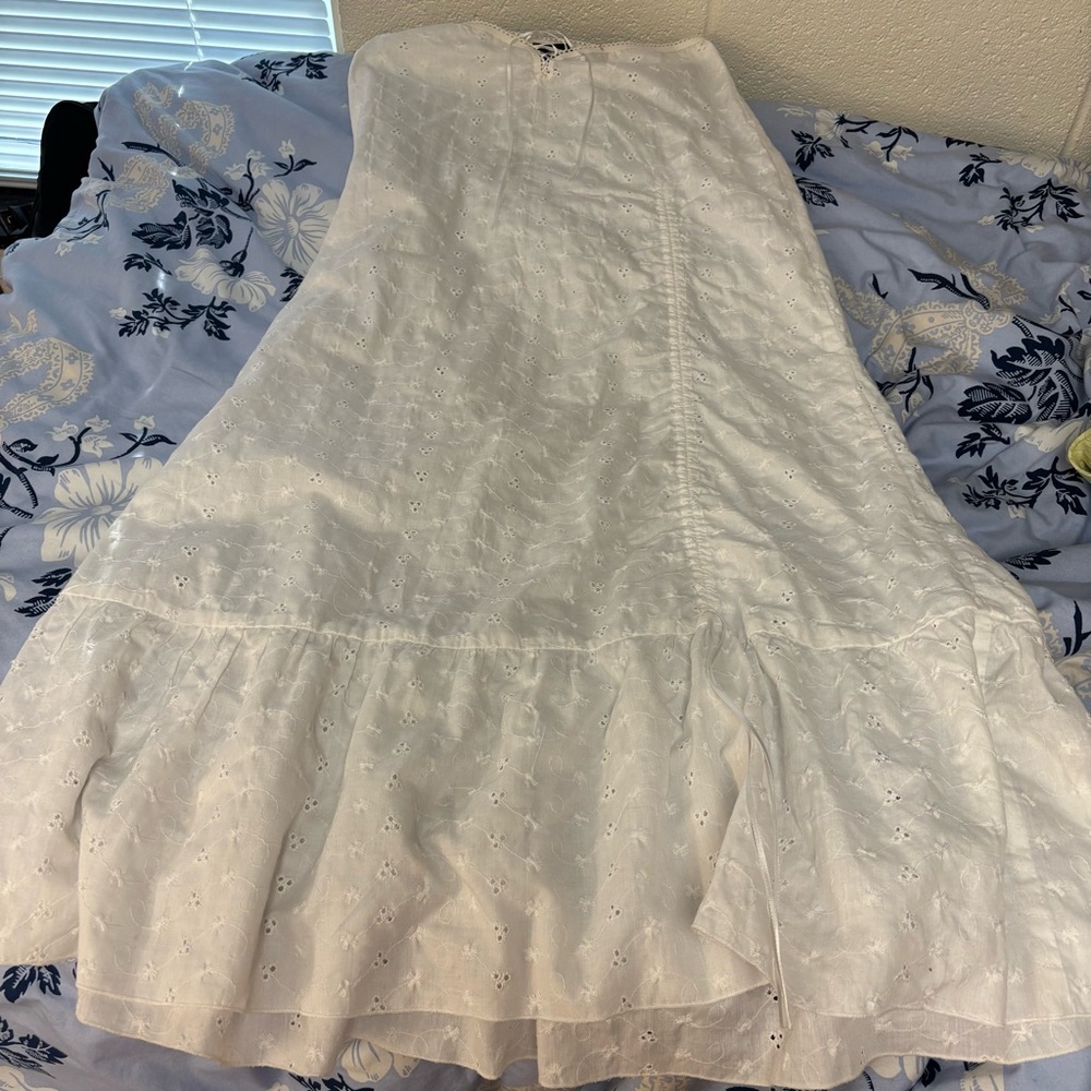 White maxi skirt with a lace at the waist, cinch near bottom, and ruffle at hem